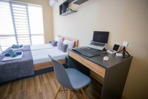 a bedroom with a bed and a desk with a laptop at Trendy Studios with FREE PARKING in Veliko Turnovo in Veliko Tŭrnovo