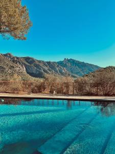 una piscina de agua azul con montañas en el fondo en Hotel-Masia Can Farrés, en El Bruc