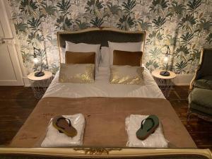 een slaapkamer met een groot bed en 2 slippers. bij Gîte et SPA La Poterne in Bergues