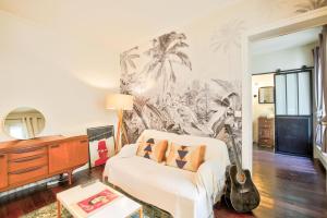 a living room with a white couch and palm trees mural at French Romanticism in Paris