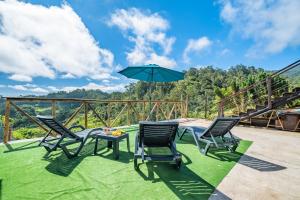 un patio con quattro sedie e un tavolo con ombrellone di São Jorge Cottage a Santana