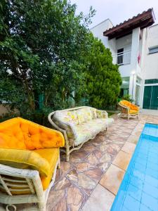 a patio with two chairs and a couch next to a pool at HOSTEL FAMÍLIA CASTOR in Itanhaém