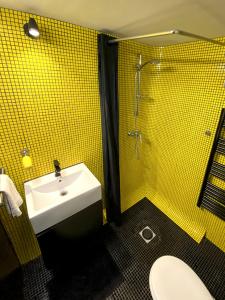 a yellow tiled bathroom with a sink and a shower at Atelier d'artiste / artist loft / 35m2 in Paris