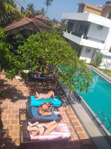 two people laying on towels next to a swimming pool at Green Wood Villa Negombo in Negombo