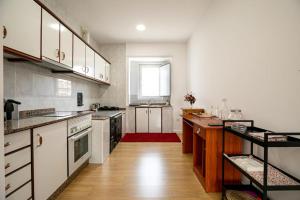 a kitchen with white cabinets and a red rug at Alola in Lousame