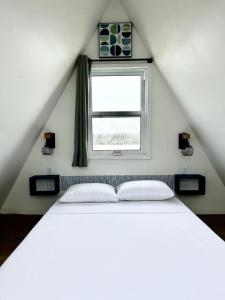 un letto bianco in una stanza con finestra di Beachfront Cabin a San Pedro