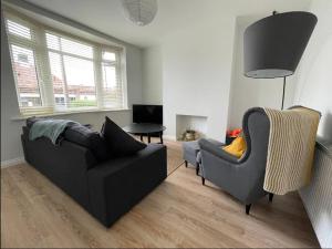 a living room with a black couch and two chairs at Modern 3 bedroom home, close to City Centre and Peak District in Heeley