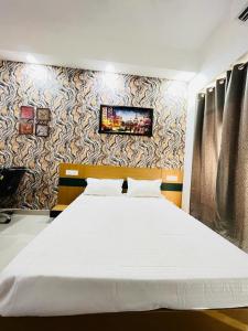 a bedroom with a large bed with a tv on the wall at Gaur City Centre in Ghaziabad
