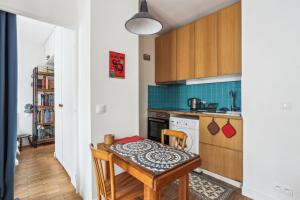 a kitchen with a table and a small kitchen with blue tiles at Le Cosy Pantin - France in Pantin