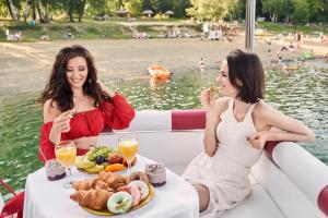 Duas mulheres sentadas num barco a comer comida. em VIP JACHT em Polańczyk