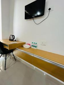 a desk with a television on a wall with a chair at Gaur City Centre in Ghaziabad