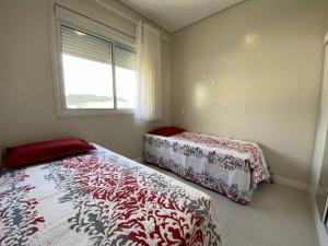 ein Schlafzimmer mit einem Bett und einem Fenster in der Unterkunft Miss Sarajevo Praia Palmas Governador Celso Ramos in Governador Celso Ramos + 9 Fotos