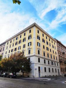 Luxury Suites - Stay Inn Rome Experience في روما: مبنى أصفر كبير فيه سيارات متوقفة أمامه