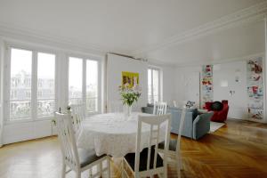 una sala da pranzo bianca con tavolo e divano di Spacious apartment with 3 bedrooms - Tour Eiffel a Parigi