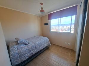 a bedroom with a bed and a large window at Departamento completo sector aeropuerto La Serena in La Serena