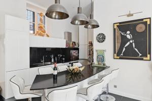 a kitchen with a black table and white chairs at Le Luxe à la Française in Paris