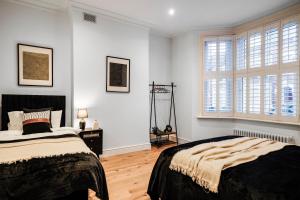 a bedroom with two beds and two windows at Classy House in Maida Vale - Private Garden in London