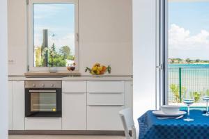 a white kitchen with a table and a window at Villa Miri Rosemary in Privlaka