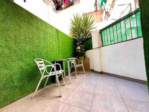 two chairs and a table in front of a green wall at T5 Apartment with terrace and sun next the metro T5 in Barcelona