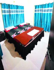 łóżko w pokoju z niebieskimi zasłonami w obiekcie Goroomgo New Sriyansh Puri w mieście Puri