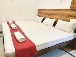 チェンナイにあるNile Guest Houseの白と赤のシーツが備わる客室のベッド2台