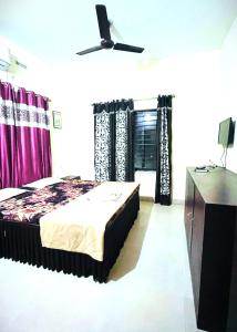 a bedroom with a bed with purple curtains at Goroomgo New Sriyansh Puri in Puri