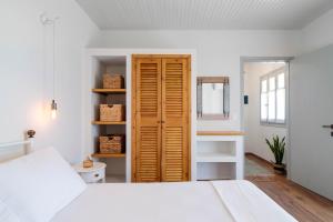 a bedroom with a white bed and a wooden door at Green Mountain Seaview Suite in Achílleion