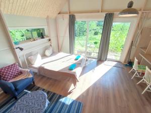 a bedroom with a bed and a couch and a window at Modern Sauna Cabin in Horse Ranch in Lieplaukė