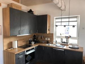 eine Küche mit schwarzen Schränken, einem Waschbecken und einem Fenster in der Unterkunft Wehrmietung in Wanfried