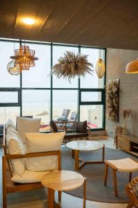 a living room with a couch and tables and windows at Blpl Cabane A luxury beach house in Karachi