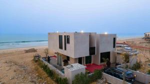 a house on the beach with a car parked in front at Blpl Cabane A luxury beach house in Karachi