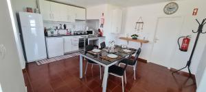 cocina con mesa, sillas y nevera en Casa Miramar, en Algarvia