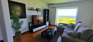 a living room with a couch and a flat screen tv at Casa Miramar in Algarvia