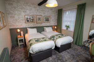 2 camas en una habitación de hotel con cortinas verdes en Rockingham Arms By Greene King Inns en Wentworth