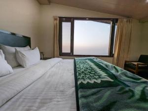 a bedroom with a large bed with a window at Summer Capital BnB in Shimla