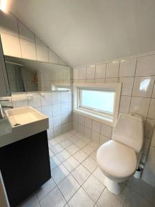 a bathroom with a toilet and a sink and a window at Central family twinhouse in Stavanger