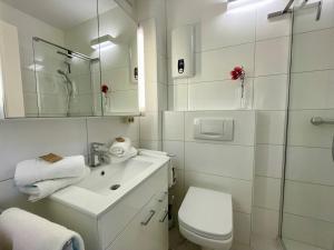 uma casa de banho branca com um lavatório e um WC em Haus Kampbarg Suite 2-Meer-Blick em Kampen