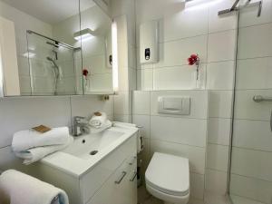 a white bathroom with a sink and a toilet at Haus Kampbarg Suite 2-Meer-Blick in Kampen +14 photos