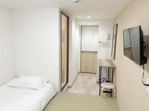 a small room with a bed and a television at da inn in Osaka