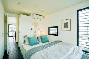 a bedroom with a bed with blue pillows at Exklusives Ostsee-Hausboot, Küche mit Spüler, Tv, große Sonnenterrasse, 3x kostenfreie Kfz-Parkplätze, Klimaanlage, bis zu 6 Personen, 2x Bäder, Waschmaschine in Boltenhagen