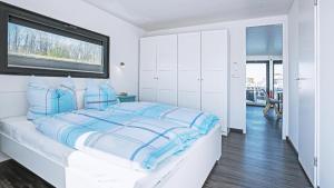 a white bedroom with a large bed with blue stripes at Geiseltalsee Hausboot - Floating House - Hausboot Junior in Braunsbedra