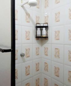 a bathroom with a white tiled wall with a shelf at Casa Playa Los Marinos in Puerto Baquerizo Moreno