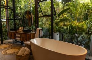 uma banheira numa casa de banho com plantas em Exôtico Beach & Rooms em Puerto Viejo