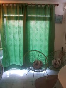 duas cadeiras em frente a uma janela com cortinas verdes em MER ET SOLEIL em Port-Louis