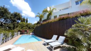 a swimming pool with two chairs and a fence at Exquisite Villa Near Beach - Heated Pool in Marbella