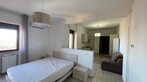 a white bedroom with a bed and a chair at Il Rifugio Nel Cielo in Termoli