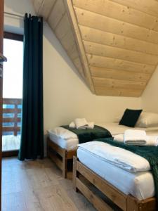 twee bedden in een kamer met een houten plafond bij WierchoHouse in Groń