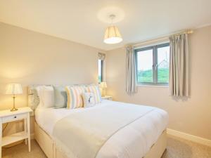 a bedroom with a large white bed with a window at Beautiful Seaside Holiday Home in West Bay
