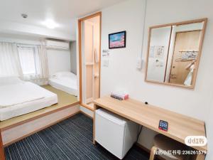 Cette chambre comprend un lit, un bureau et un miroir. dans l'établissement da inn, à Osaka