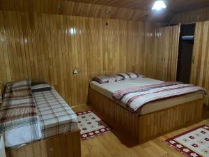 a bedroom with two beds in a wooden room at Yildirim Aile Pansiyonu in Sultan Murat Yaylasi